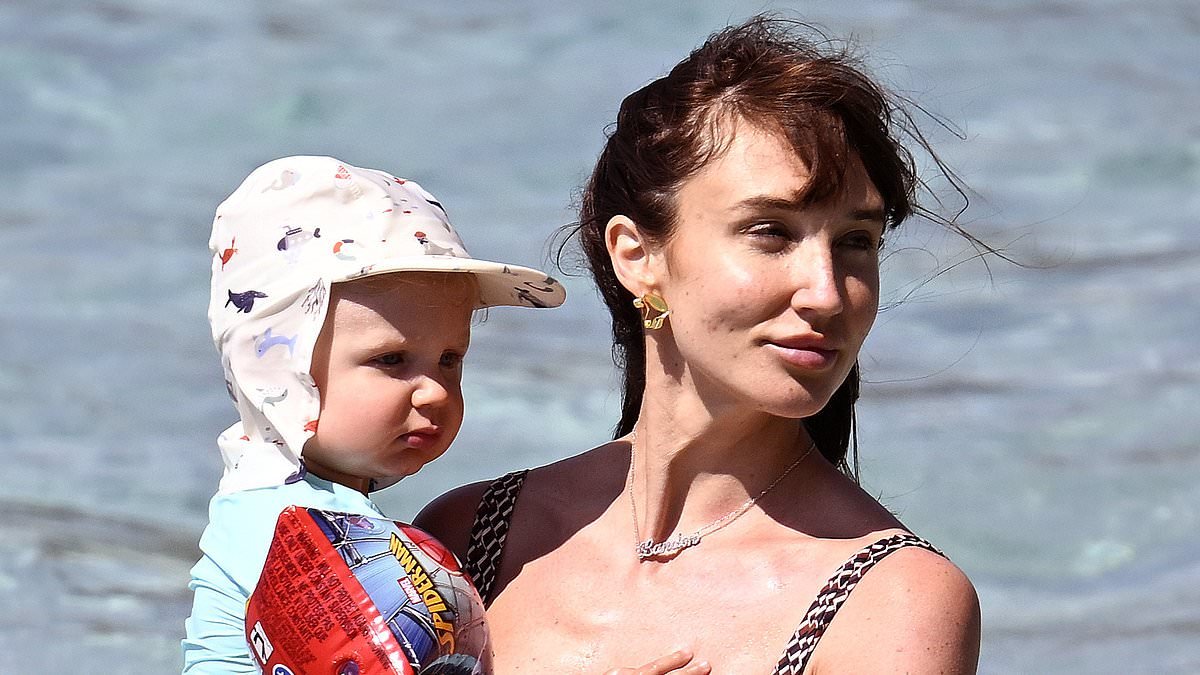 Megan McKenna shows off her gorgeous figure in a plunging swimsuit as she hits the beach with husband Oliver Burke and son Landon, 19-months, amid family getaway in Mallorca