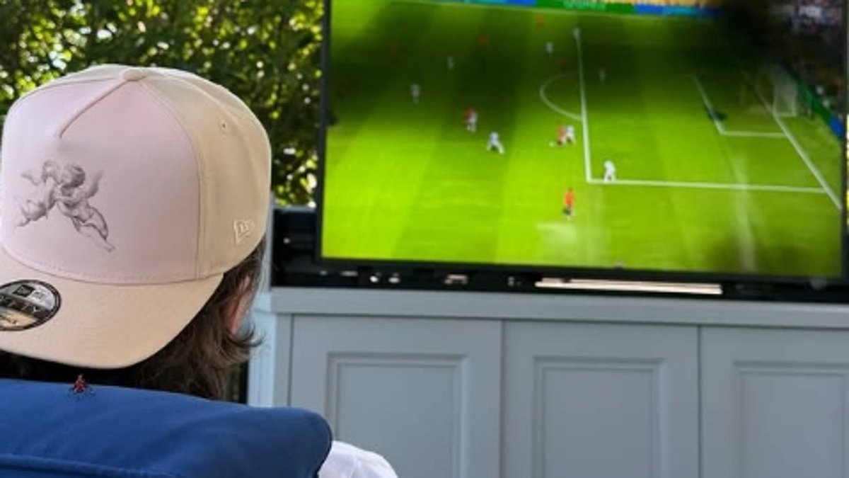 Brooklyn Beckham watches the World Cup final from his sofa at home as his entire family support from the MetLife Stadium - after savage Door Dash ad