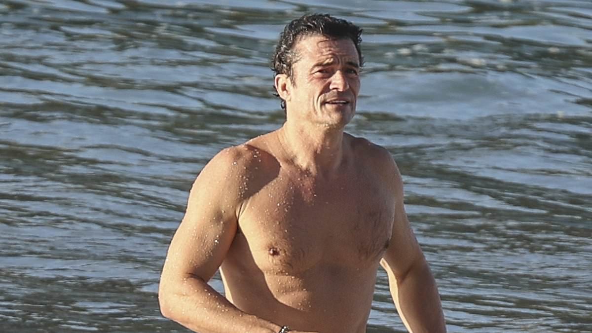 Orlando Bloom, 49, shows off his ripped physique as he emerges from the sea after a swim in Spain