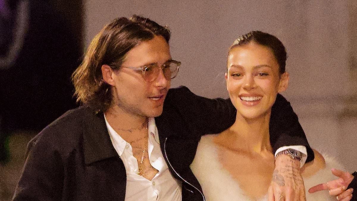 Brooklyn Beckham and ab-flashing Nicola Peltz pack on the PDA during a night out in Paris after snubbing his mum Victoria's show as the designer gushes she feels 'so blessed' to have the rest of her family supporting her