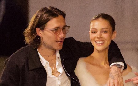 Brooklyn Beckham and ab-flashing Nicola Peltz pack on the PDA during a night out in Paris after snubbing his mum Victoria's show as the designer gushes she feels 'so blessed' to have the rest of her family supporting her